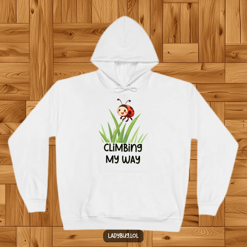 Funny giggling ladybug character enthusiastically climbing a blade of grass, featured on a cozy hoodie for humorous warmth.