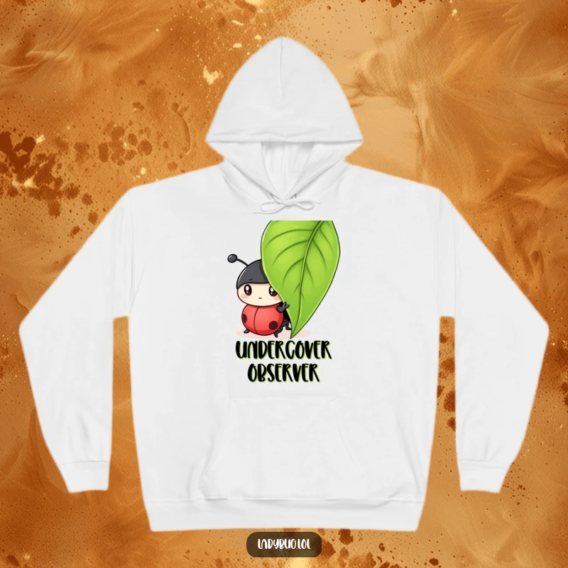 Funny hoodie featuring a curious ladybug character peeking from under a leaf, hinting at playful secrets.